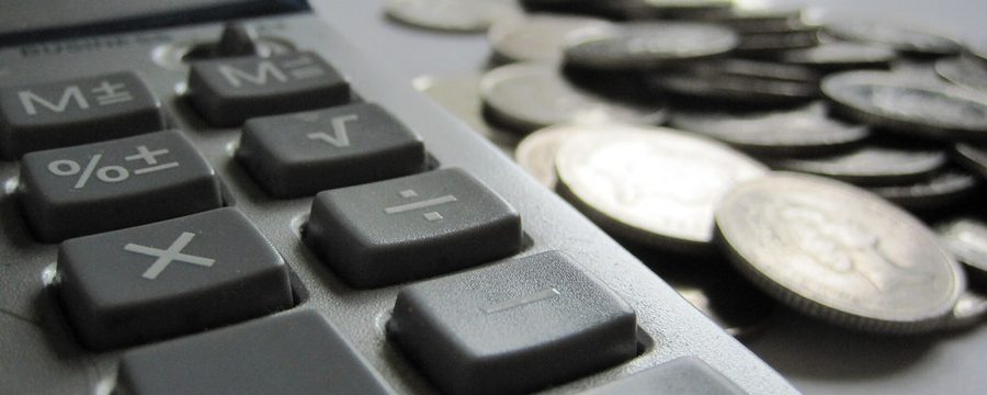 Taschenrechner neben einem Stapel Münzen